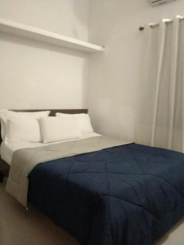 a bedroom with a bed with a blue blanket at Gennys Farm House in Sawantwadi