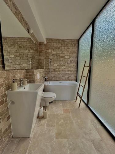 a bathroom with a tub and a toilet and a sink at Zafra Chalet in Poiana Ţapului