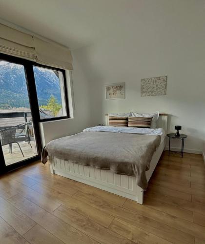 a white bedroom with a bed and a large window at Zafra Chalet in Poiana Ţapului