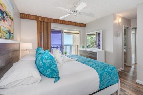 a bedroom with a large white bed with blue pillows at Hololani B204 · HL B204 Beachy Chic Updated OceanFront 2BD in Kahana