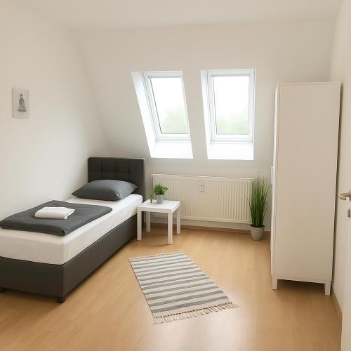 1 Schlafzimmer mit einem Bett, 2 Fenstern und einem Teppich in der Unterkunft SUNNYHOME Monteurwohnungen und Apartments nahe Regensburg in Nittendorf
