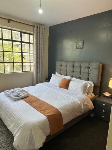 a bedroom with a large bed with white sheets and orange pillows at Eden Space Accommodations in Nairobi