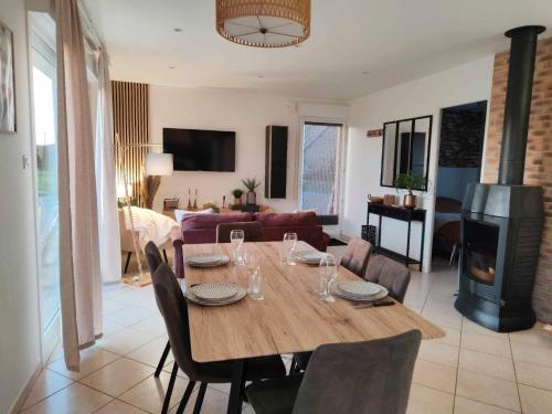 a dining room table with chairs and a living room at Gîte De L 'entre 2 Côtes in Vindefontaine