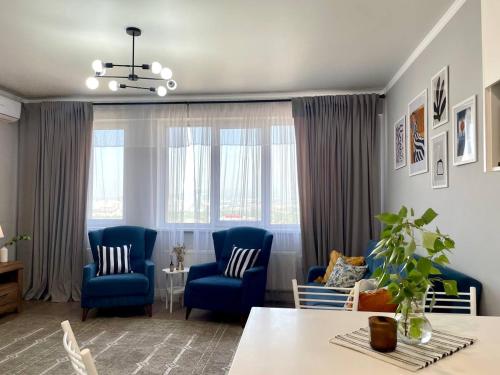 ein Wohnzimmer mit blauen Stühlen und einem Tisch in der Unterkunft Terra с шикарным видом на горы, рядом ТРЦ Mega по розыбакиева in Almaty