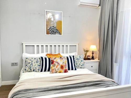 ein weißes Bett mit Kissen darauf im Schlafzimmer in der Unterkunft Terra с шикарным видом на горы, рядом ТРЦ Mega по розыбакиева in Almaty