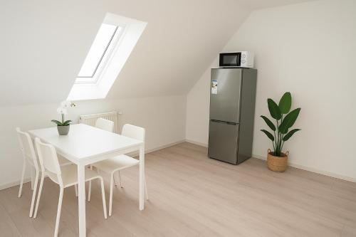ein Esszimmer mit einem weißen Tisch und einem Kühlschrank in der Unterkunft SUNNYHOME Monteurwohnungen und Apartments nahe Regensburg in Nittendorf