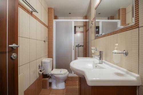 a bathroom with a sink and a toilet and a mirror at Meliton Inn Hotel & Suites by the beach in Neos Marmaras