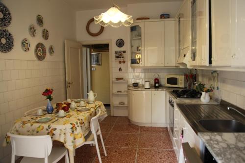 Una cocina con mesa y sillas y una cocina con gabinetes blancos. en Amarcorde Home in Corso Buenos Aires con 6 posti letto, en Chiavari