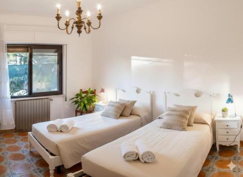 two beds in a room with a chandelier at Da Ernestina in Imperia