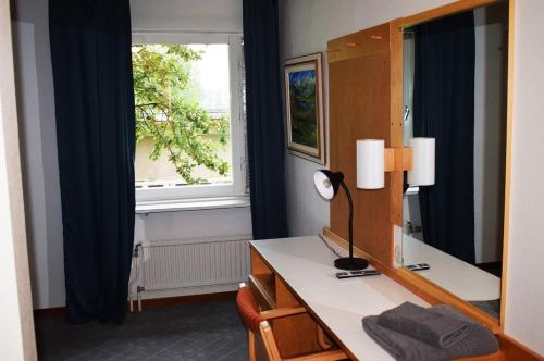 a bathroom with a desk with a mirror and a window at Åsele Wärdshus in Åsele