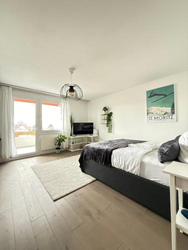 a bedroom with a bed and a large window at HRE Apartments Lago Rorschach in Rorschach