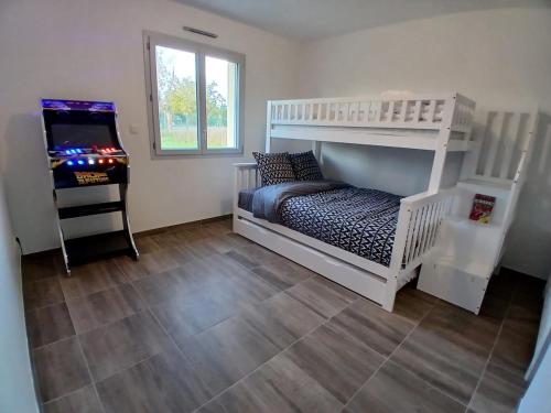 ein Schlafzimmer mit einem weißen Etagenbett und einem Videospiel in der Unterkunft Logement insolite avec Jeux et Jacuzzi in Soulosse-sous-Saint-Élophe