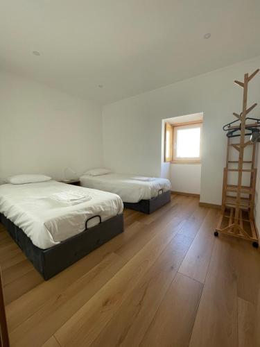 deux lits dans une chambre avec parquet et une échelle dans l'établissement Casa Catalão, à Montelavar