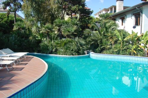 a large swimming pool with chairs and palm trees at Park Hotel Pineta Boutique Hotel in Caorle