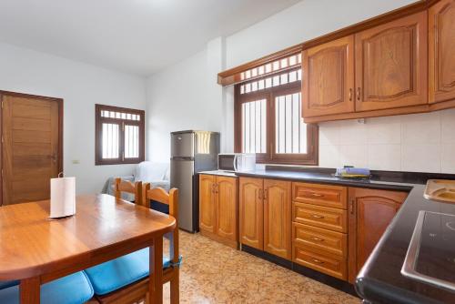 a kitchen with wooden cabinets and a table and a dining room at Home2Book Family House with Terrace in Las Maretas in La Mareta