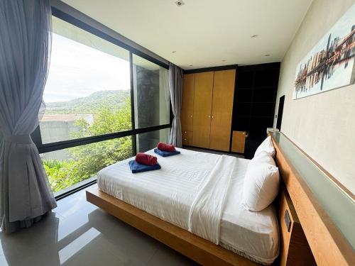 une chambre avec un lit et une grande fenêtre dans l'établissement Design Duplex Pavillion 2 BR Natural Park P11, à Kamala Beach