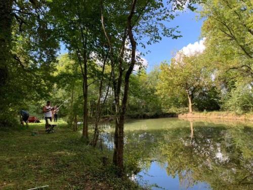 a person standing next to a lake with a fishing rod at Liguand Gites in Saint-Quentin-du-Dropt