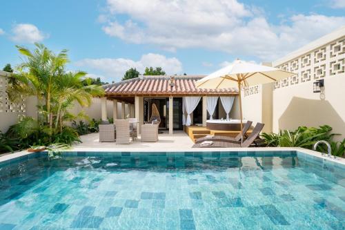 a swimming pool with chairs and an umbrella at THE GARDEN Bise ザガーデンビセ ｰ沖縄北部本部町備瀬にあるラグジュアリーヴィラｰ"オープン記念特別ご優待" in Motobu