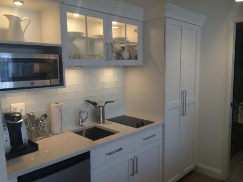 a kitchen with white cabinets and a sink at ICONA Avalon in Avalon