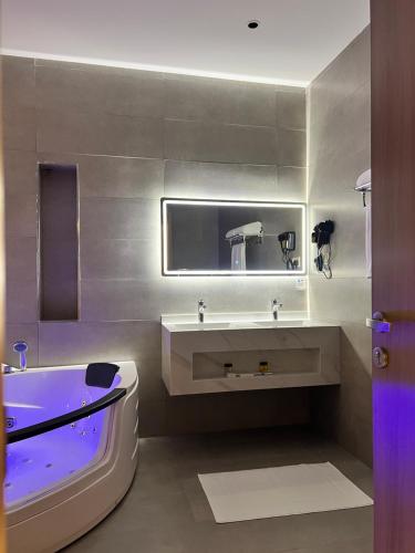 a bathroom with a tub and a sink and a bath tub at فندق دبليو سويتس القنفذة in Al Qunfudhah