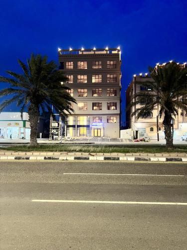 a building with palm trees in front of a street at فندق دبليو سويتس القنفذة in Al Qunfudhah