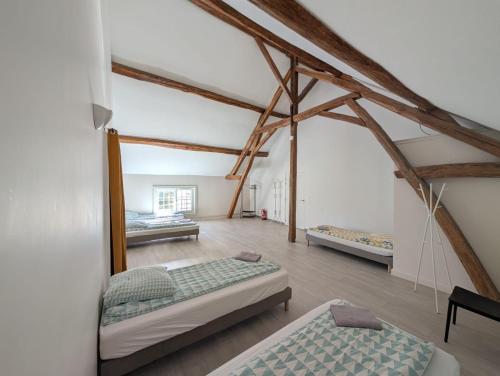 a room with three beds in it with wooden beams at Crazy Villa Etisseaux 45 - Heated pool - Volley court - 1h30 Paris - 45p in Saint-Maurice-sur-Aveyron