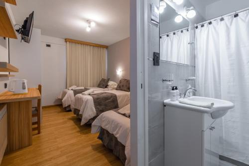 a hotel room with three beds and a sink at Hotel Sol del Sur in Esquel