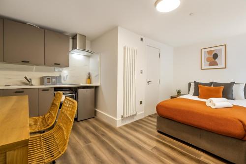 a bedroom with an orange bed and a kitchen at The Little Venice Studios in London