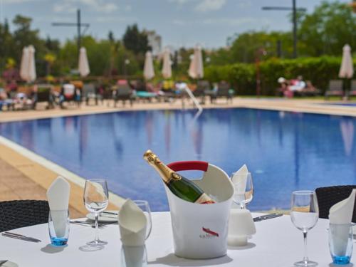 a bottle of wine sitting on a table next to a pool at Dom Pedro Portobelo in Vilamoura