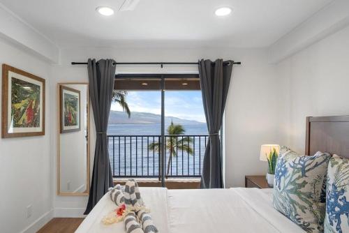a bedroom with a bed with a view of the ocean at Lauloa 403 · LOA 403 Fully Remodeled Direct Oceanfront 2BD in Wailuku