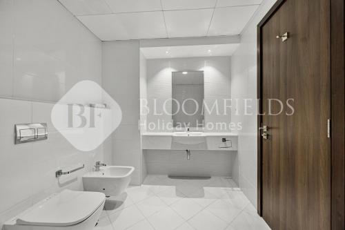 a white bathroom with a toilet and a sink at Bloomfields Elegance 2br Ajwan Soul Beach Access in Abu Dhabi