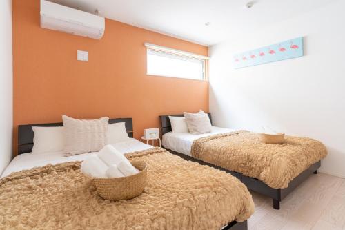 2 Betten in einem Zimmer mit orangefarbenen Wänden in der Unterkunft Grandioso Onna 7-D - Vacation STAY 86760v in Atsutabaru