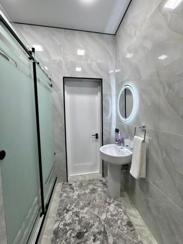 a white bathroom with a sink and a mirror at Town House in Samarkand