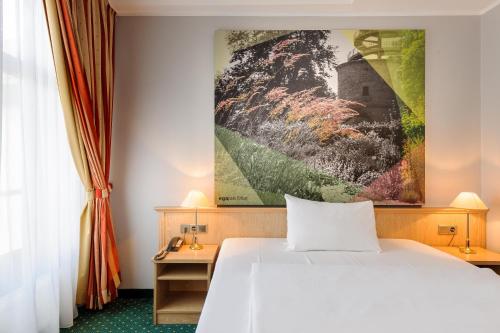 a bedroom with a white bed and a painting on the wall at Mercure Hotel Erfurt Altstadt in Erfurt