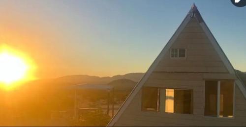 a view of a house with the sunset in the background at Arlo's AFrame in Joshua Tree