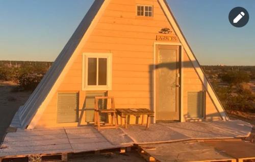 a house with a table and a chair in front of it at Arlo's AFrame in Joshua Tree