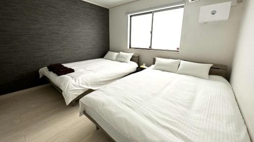 zwei Betten in einem kleinen Zimmer mit Fenster in der Unterkunft Grandioso Onna 7-D - Vacation STAY 17402v in Atsutabaru