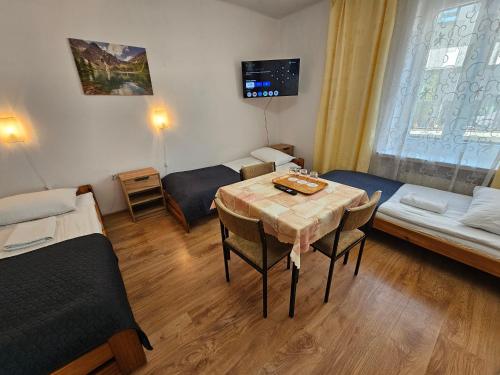 热舒夫Hotel Eden 24h的一间带桌子的房间和一间带两张床的房间