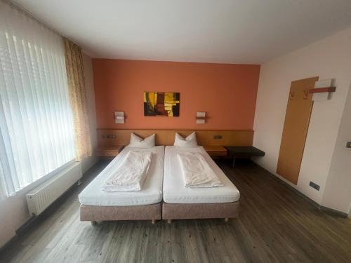 ein großes Bett in einem Zimmer mit orangefarbener Wand in der Unterkunft Hotel Casa Nostra in Schloß Holte-Stukenbrock