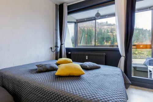 a bedroom with a bed with yellow pillows and a window at Le Cocoon de Belle Hutte sous les sapins in Xonrupt-Longemer