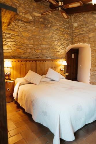 a bedroom with a large white bed in a stone wall at Hotel Mas Rabiol -Emporda-Only Adults-Eco Hotel in Peratallada