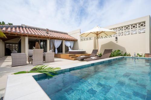a pool with chairs and an umbrella next to a house at THE GARDEN Bise ザガーデンビセ ｰ沖縄北部本部町備瀬にあるラグジュアリーヴィラｰ"オープン記念特別ご優待" in Motobu