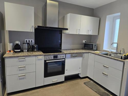 a kitchen with white cabinets and a stove top oven at Appartement proche Walibi in Les Avenières