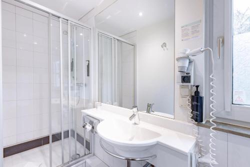 Un baño blanco con lavabo y ducha en Garner Hotel Bremen North by IHG, en Bremen