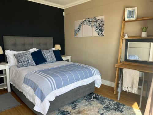 a bedroom with a bed with a blue and white comforter at Oceana Views in Gordonʼs Bay