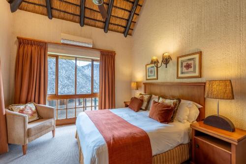 a bedroom with a bed and a chair and a window at Kruger Park Lodge Unit No 237 in Hazyview