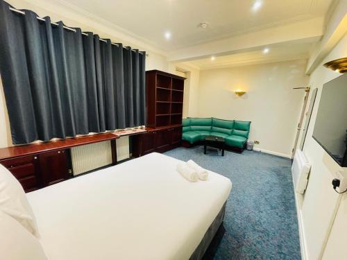 a hotel room with two beds and a green chair at TCH Lodge in Bolton