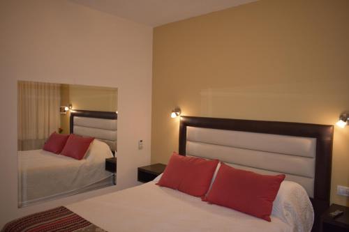 - une chambre avec un lit doté d'oreillers rouges et d'un miroir dans l'établissement Aparts Solares, à San Antonio de Arredondo