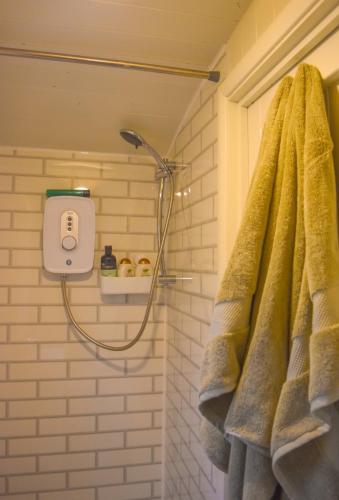 a shower in a bathroom with a yellow towel at Shepherd Hut in the woods in Clothall