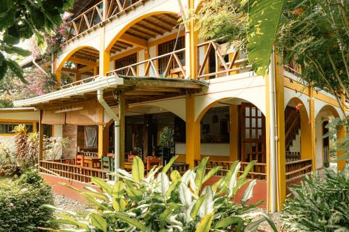 a yellow building with a balcony in a garden at Cabañas Tucan Eco Hotel in Capurganá